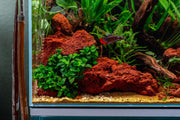 Red lava rock stone by SB, showing textured, porous surface in vibrant red color ideal for decorative or landscaping use.