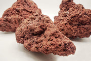 Red Lava Rock stone by SB showing textured, porous red volcanic rock with natural surface details.